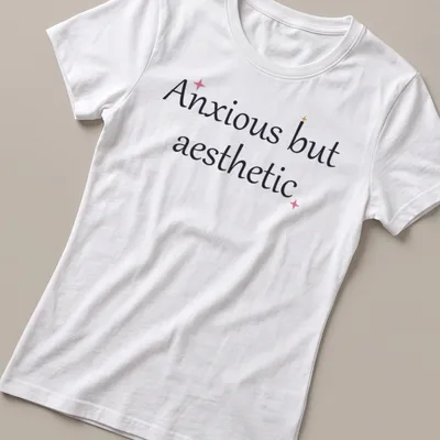 Cute mental health quote in cursive: Anxious but aesthetic, in black, pink, and gold. — printed on a women's shirt