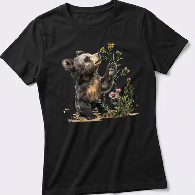 Watercolor illustration of a bear cub surrounded by flowers in soft colors — printed on a women's shirt