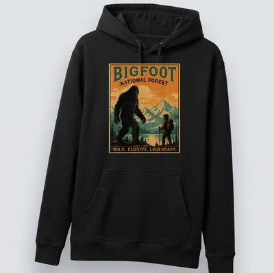 Vintage poster style Bigfoot t-shirt with bold text and forest imagery — printed on a unisex hoodie