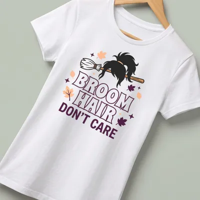 Cartoon broomstick with hair and text reading 'Broom Hair Don't Care' in Halloween colors — printed on a women's shirt