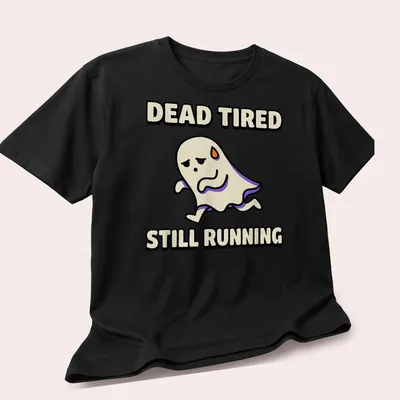 Cartoon ghost graphic with text Dead Tired Still Running in black and purple — printed on a unisex t-shirt (angled view)