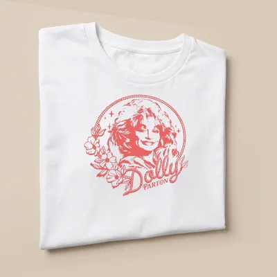 Minimalistic portrait of Dolly Parton with flowers in soft pink and white — printed on a unisex t-shirt (angled view)