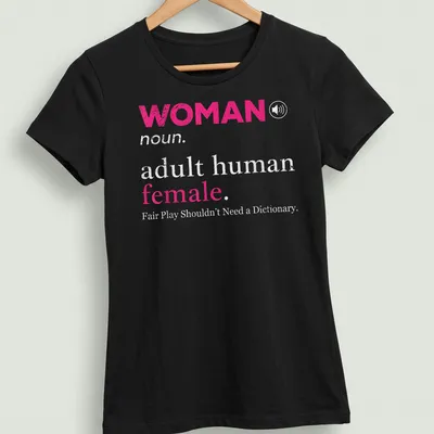 Bold typography design stating 'WOMAN noun. adult human female. Fair Play Shouldn't Need a Dictionary.' — printed on a women's shirt