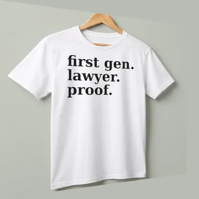 Bold typography t-shirt celebrating first-generation lawyers with black text on white background — printed on a unisex t-shirt (angled view)