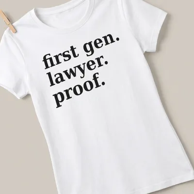 Bold typography t-shirt celebrating first-generation lawyers with black text on white background — printed on a women's shirt