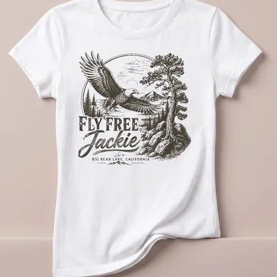 Vintage eagle graphic with text reading 'FLY FREE, Jackie BIG BEAR LAKE, CALIFORNIA' in black, white, and gray — printed on a women's shirt