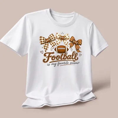 Whimsical design of footballs and bows with the text 'Football is my favorite season' — printed on a unisex t-shirt (angled view)
