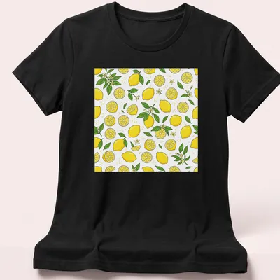 Pattern of bright yellow lemons with green leaves on a white background — printed on a women's shirt