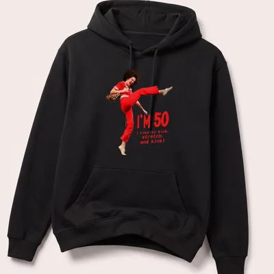 Funny 50th birthday T-shirt featuring a character kicking with humorous text — printed on a unisex hoodie