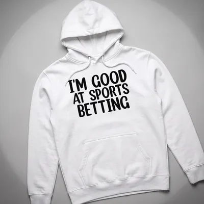 T-shirt with bold black and white typography stating I'm Good At Sports Betting — printed on a unisex hoodie