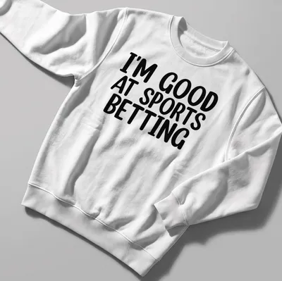 T-shirt with bold black and white typography stating I'm Good At Sports Betting — printed on a unisex sweatshirt
