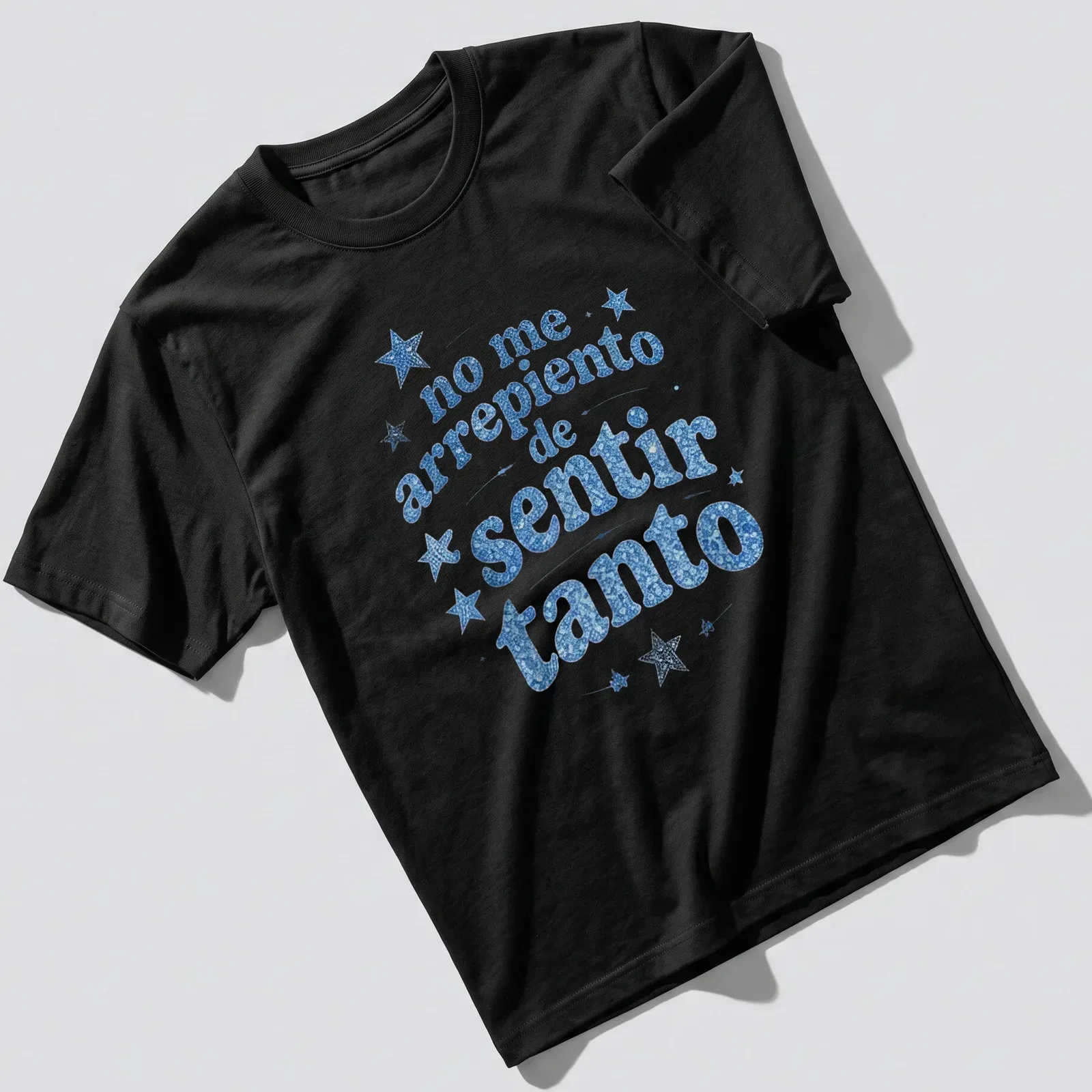 Blue glitter stars with white text reading 'no me arrepiento de sentir tanto' — printed on a unisex t-shirt
