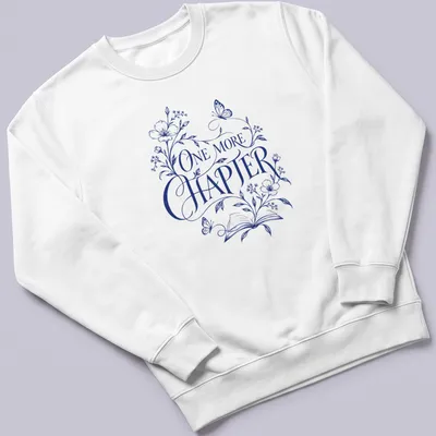Elegant botanical design featuring an open book with flowers and butterflies, and 'One More Chapter' text — printed on a unisex sweatshirt