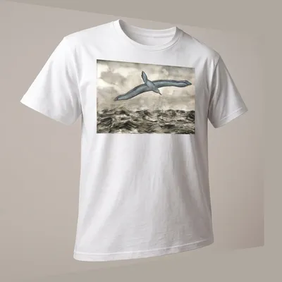 Watercolor print of an albatross flying over waves with grey, blue, and white tones — printed on a unisex t-shirt (angled view)