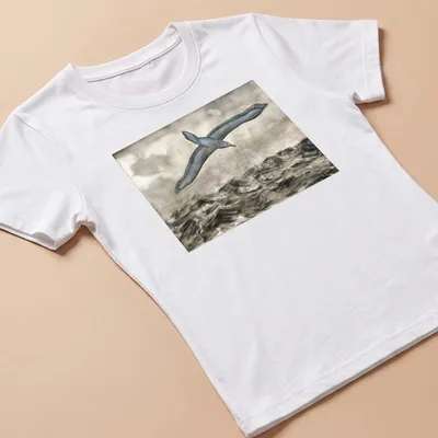 Watercolor print of an albatross flying over waves with grey, blue, and white tones — printed on a women's shirt