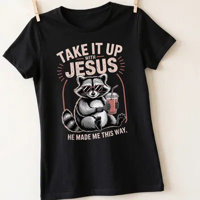 Cartoon raccoon holding a drink with humorous text about Jesus — printed on a women's shirt