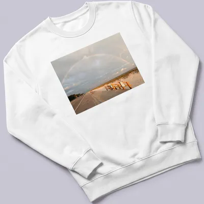 Illustration of a rainbow over a beach landscape with blue and green hues. — printed on a unisex sweatshirt
