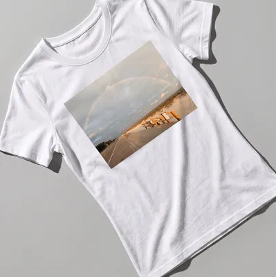 Illustration of a rainbow over a beach landscape with blue and green hues. — printed on a women's shirt