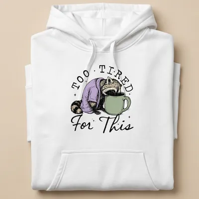 Vintage illustration of a raccoon face down in a coffee cup with playful text — printed on a unisex hoodie