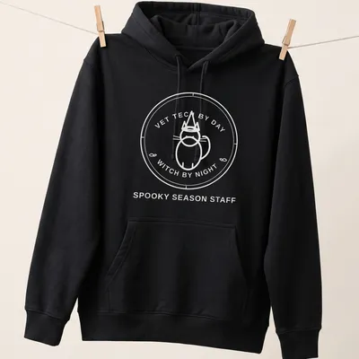 Circular badge design featuring the text Vet Tech By Day Witch By Night with a cat. — printed on a unisex hoodie