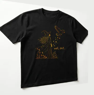 Line-art design featuring a witch and crow with the text 'well, shit..' in orange — printed on a unisex t-shirt (angled view)